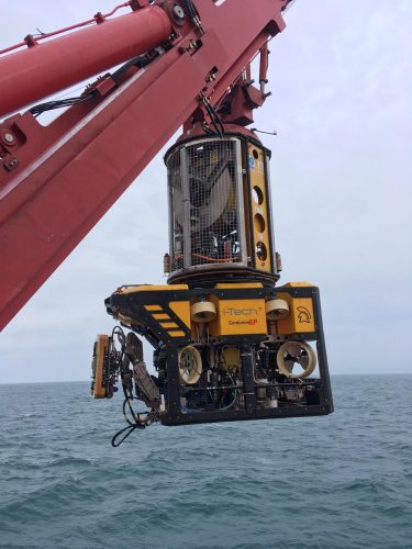 Subsea crane lifting ROV into water for inspection.